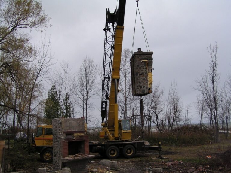Crane lifting a stone chimney section on an ICF build